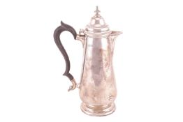 A silver hot water jug with a domed hinged cover and ebonised handle, 27cm high, London 1917, by Gol