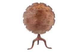 A George III mahogany snap-top wine table with shaped and moulded piecrust edge over a plain taperin