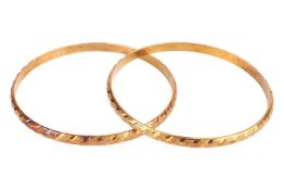 A pair of closed bangles, of diagonal design and partially textured, yellow metal marked '14', inner