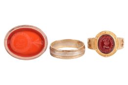 Three rings comprising a carnelian seal ring, with the monogram 'AW' and Latin motto 'nil nisi labor