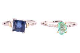 An single stone emerald ring with an oval cut emerald in raised claw mount, with two stone diamond s