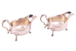 A pair of silver sauce boats; with cut-away edges and double scroll handles, on three shell- mounted