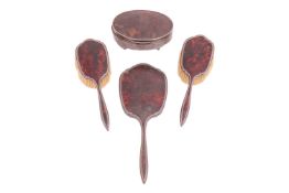A silver mounted tortoiseshell dressing table set comprising two hairbrushes, a hand mirror and an o