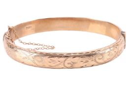 A 9ct gold hinged bangle, with half of the hollow bracelet engraved with bright-cut scrollwork patte