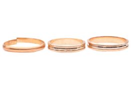 Three rings; comprising two bi-colour bands, of angular reeded design, tested as 18ct gold, sizes N 
