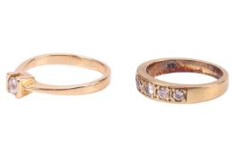 Two rings comprising a solitaire ring, featuring a CZ in a semi-bezel setting, to a yellow metal sha