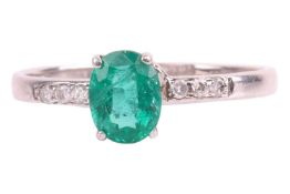An emerald and diamond ring, the emerald claw set and flanked by shoulders of three mixed-cut diamon