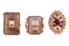 Three rings; comprising two smokey quartz cocktail rings, both featuring octagonal-cut smokey quartz