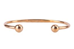 A torque bracelet in 9ct yellow gold, with spherical terminations, struck with Birmingham assay mark