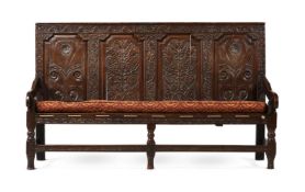 A CARVED OAK FOUR PANEL SETTLE