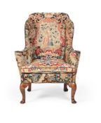 A WALNUT AND NEEDLEWORK UPHOLSTERED WING ARMCHAIR