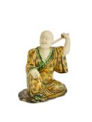 ‡ A STAFFORDSHIRE CREAMWARE FIGURE OF A LOHAN CIRCA 1750 The seated disciple of Buddha scratching h