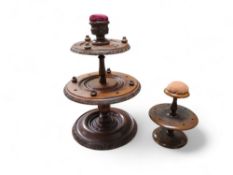 A 19th century mahogany seamstress's circular two-tier cotton bobbin stand, pin cushion finial, 27cm
