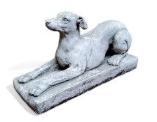 A reconstituted stone recumbent greyhound, plinth base, 46cm in length