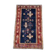 A West Persian Luribaft hand knotted wool rug with repeat foliate motif on dark blue and brick red