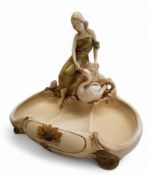 A Royal Dux model, of a lady with a swan, seated by a pool, in relief with flowers and sinuous