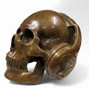 A novelty patinated bronze human skull wearing headphones, 15.5cm high