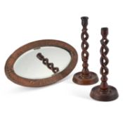 A SMALL ARTS AND CRAFTS COPPER-MOUNTED OVAL MIRROR AND A PAIR OF OAK OPENTWIST CANDLESTICKS