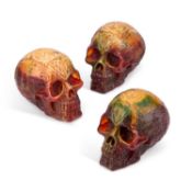 THREE AMBER-COLOURED RESIN SKULLS