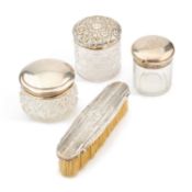 THREE SILVER-TOPPED GLASS DRESSING TABLE JARS AND A SILVER-BACKED BRUSH