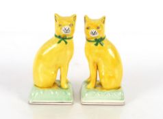 A pair of Staffordshire yellow glazed figures of seated cats on cushions, 20cm high