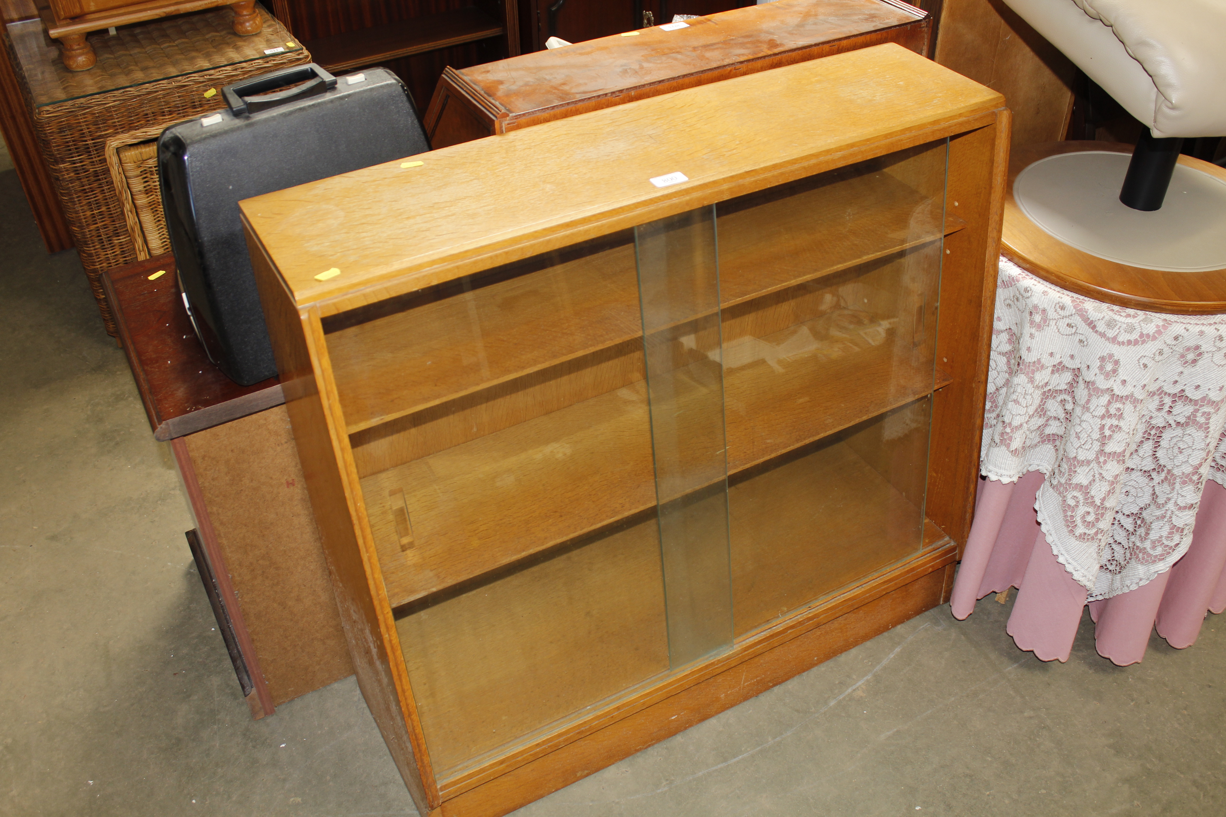 A golden oak bookcase fitted with sliding glass do