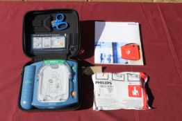 A Philips HeartStart defibrillator in hard carry case, with owners manual, and a smart pad cartridge