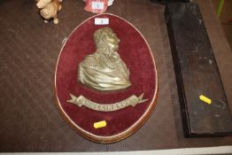 A bronzed plaque depicting head and shoulders stud