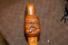 A carved walking stick, the head in the form of Wi