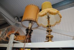 A brass table lamp and shade and a wooden candlest
