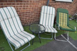 Three Garden Lounge Chairs and a Small Glass Topped Table