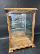 A glass tabletop display case with three adjustable glass shelves and mirrored back, 17 1/4
