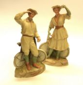 A pair of figurines by Gebruder Heubach. 'Bisque' figurines of a boy and girl bicycle riders, c.