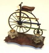 An inkwell and pen compendium in the form of an Ordinary bicycle, the wooden saddle hinging to