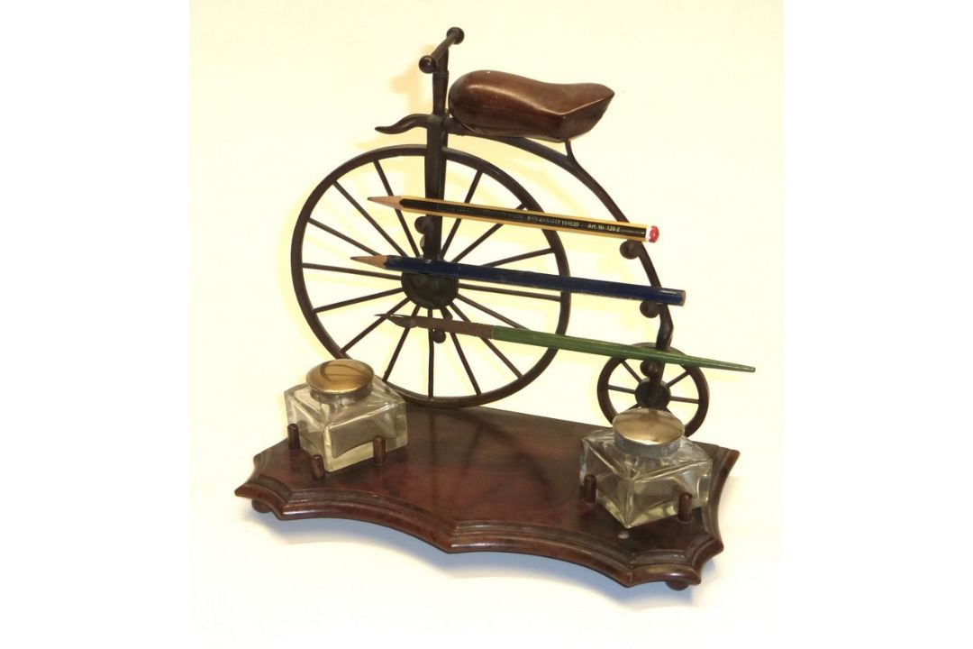 An inkwell and pen compendium in the form of an Ordinary bicycle, the wooden saddle hinging to