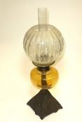 A domestic oil lamp having four-sided cast metal image of a lady cyclist, amber glass oil reservoir,