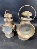 Two early brass paraffin lamps: Powell & Hanmer and Lucas King of The Road.