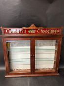 A two-door wall hanging cabinet with two glass shelves with advertising for Cadbury's Chocolates