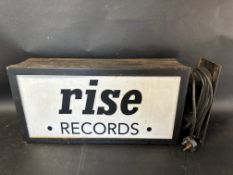 A double sided metal bound wall mounted lightbox advertising Rise Records to one side and Friska