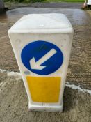 A plastic road light bollard with directional left arrow to one side.