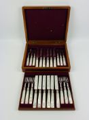 A two tier mahogany cased set of decorative mother and pearl knives and forks
