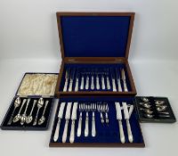 A two tier mahogany cased part set of decorative mother and pearl knives and forks