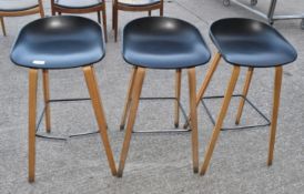 4 x Bar Stools Featuring Black Moulded Seats and Light Wooden Legs with Foot Rests