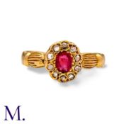A Ruby And Diamond Cluster Ring in yellow gold, set with a principal oval cut ruby within a border