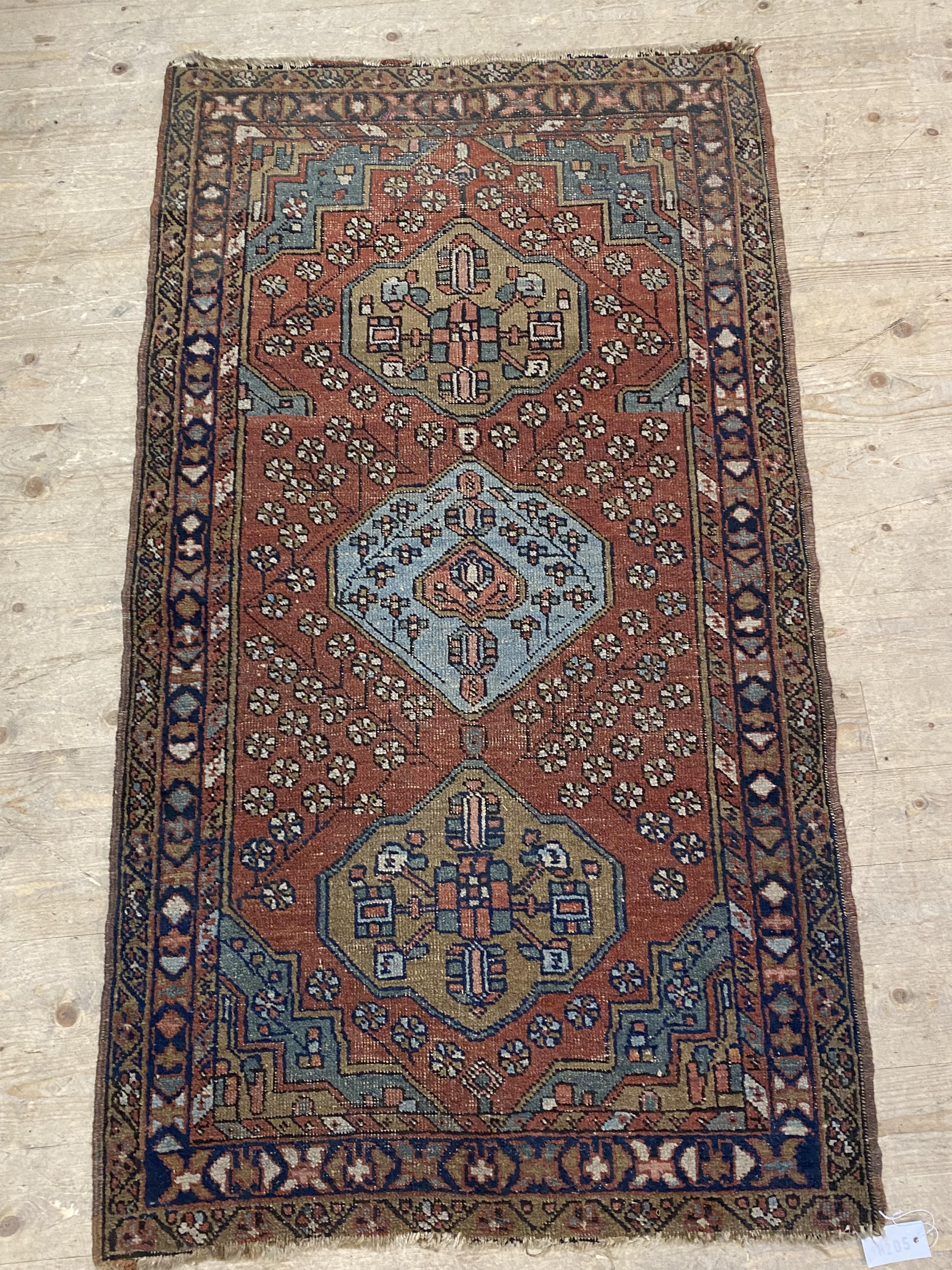 An early 20th century Persian Heriz design rug, the red field with triple medallion and decorated