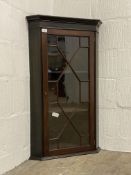 An Edwardian mahogany wall hanging corner cabinet, with an astragal glazed door enclosing two