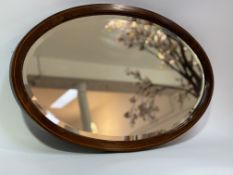 An Edwardian oval mahogany decorative mirror. (70cmx41cm)
