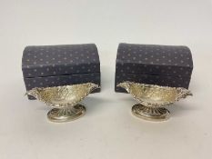 Pair of silver boat shaped salts with embossed decoration, in domed cardboard trunk-type boxes