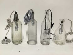 Four glass bottle hanging lanterns, one a measuring jug, another a soda siphon, each with cord fitti