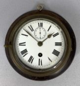 BRASS CASED SHIPS BULKHEAD CLOCK, mounted on an oak board, the white enamel dial with Roman numerals